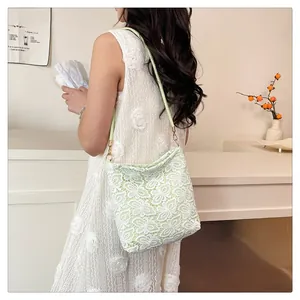 Close-up of light green shoulder bag featuring intricate white floral lace and gold buckles