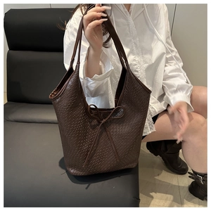 Macro detail of coffee brown woven tote bag with decorative bow and textured surface