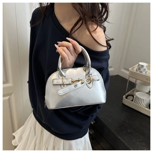 Detail of metallic silver mini shell bag with decorative cross straps and golden hardware