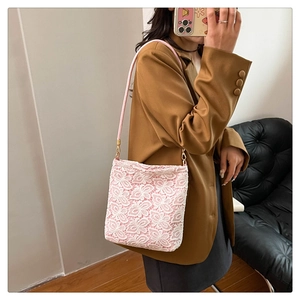 Close-up of pink lace shoulder bag featuring floral texture and golden metal hardware