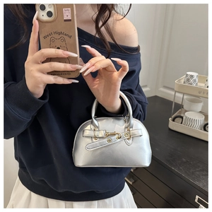 Detail of silver shell bag with golden hardware buckle and decorative strap