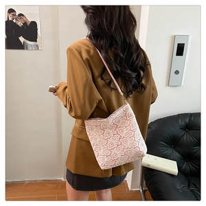 Close-up of floral lace shoulder bag featuring pink leather strap and embroidery detail