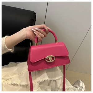 Detail of fuchsia leather handbag featuring a prominent gold V-shaped metal clasp buckle