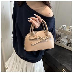 Dettaglio mini borsa a conchiglia in pelle beige con hardware dorato e fibbia in metallo