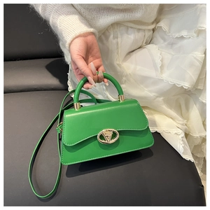 Close-up of bright green handbag featuring a gold buckle and elegant top handle