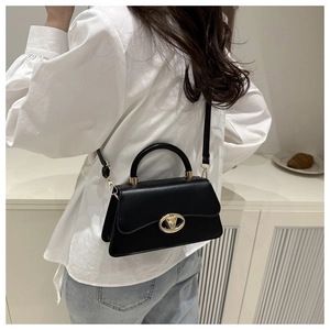 Gros plan d'un sac bandoulière en cuir noir avec boucle dorée porté par une personne