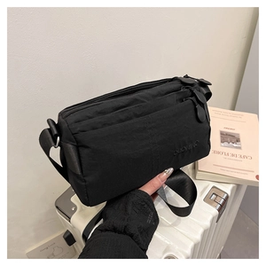 Gros plan du sac bandoulière en nylon noir avec fermetures éclair et logo discret