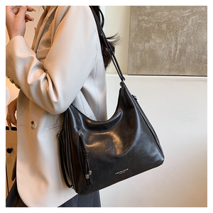 Detail of a black hobo shoulder bag featuring a silver logo and long tassel zipper