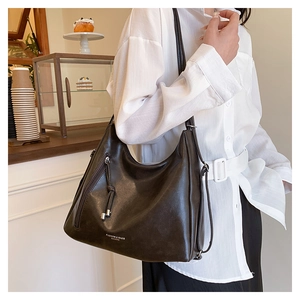 Detail of dark brown faux leather tote bag with tassel zipper and fashion logo