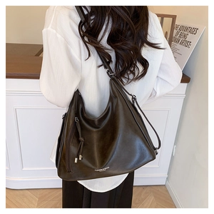 Rear view of dark brown oversized leather hobo bag with knotted tassel detail and logo
