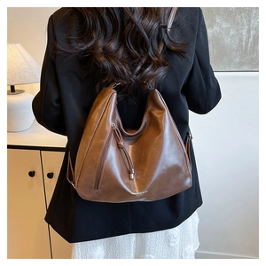 Vue arrière d'un mannequin portant un grand sac cabas en cuir marron foncé avec fermeture éclair