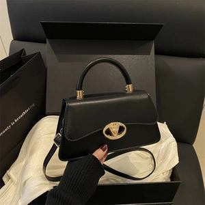 Elegant black leather handbag with gold V buckle shown in a luxury gift box setting