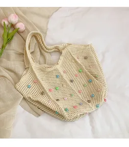 Close-up of off-white woven crochet tote bag with colorful pearl beads on soft fabric
