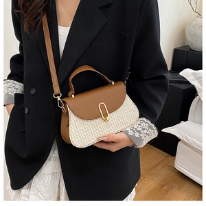 Détail de la poignée en cuir marron et du fermoir doré ovale sur le sac bandoulière tissé