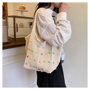 Close-up of a handmade crochet tote bag with colorful pearl beads in a cafe setting