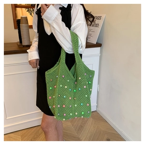 Close-up of green crochet tote bag with colorful pearls and openwork mesh texture