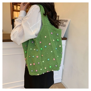 Detail of green crochet tote bag featuring multi-colored pearls and handmade texture