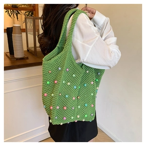 Detail of hand-knitted green tote bag with colorful macaron pearls and woven texture