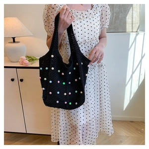 Detail of black crochet tote bag featuring colorful faux pearl embellishments and a soft knit