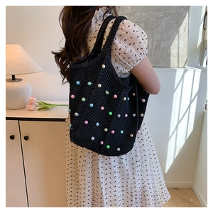 Detail of black crochet tote bag with colorful pearl accents and woven strap