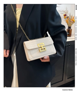 Detalle de bolso bandolera blanco con textura de cocodrilo, hebilla y cadena dorada