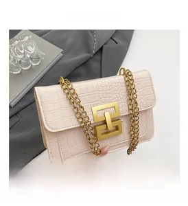 Detalle del bolso blanco crema con grabado de cocodrilo y cierre metálico dorado