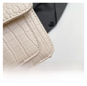 Primer plano de la textura de cocodrilo blanco crema y costuras finas en el bolso pequeño cuadrado