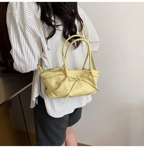 Detail of soft yellow ruched bucket bag with bow accent and crossbody strap