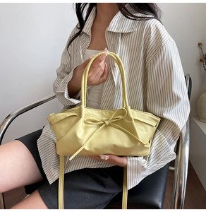 Close-up of light yellow pleated tote bag featuring delicate bow tie detail and soft texture
