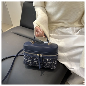 Detail of vintage navy blue leather and tweed box bag with gold metal hardware