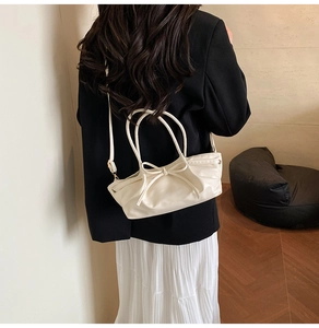 Rear view of model carrying a white leather pleated tote bag with bow detail