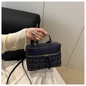 Detail of navy blue vanity bag with tweed texture, golden metal handle and zip closure