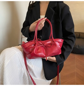 Detail of red dumpling bag with ruched texture and matching bow accent for women