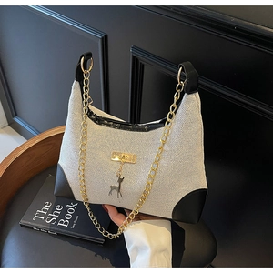 Close-up of contrast canvas shoulder bag with black leather trim and golden deer pendant