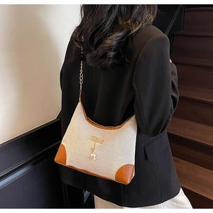 Detailed back view of canvas tote bag with brown leather trim and golden chain strap