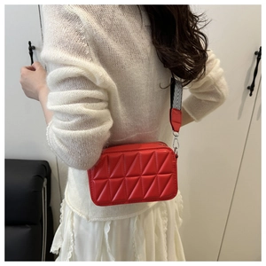Dettaglio della borsa a tracolla trapuntata rossa con trama geometrica e tracolla a righe