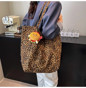 Dettaglio della borsa tote leopardata con ciondolo burger in peluche indossata dal modello