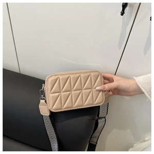 Dettaglio della borsa a tracolla beige trapuntata con cuciture a triangolo e tracolla a spina