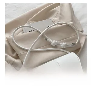 Detail of white leather bag featuring a knotted shoulder strap and silver metal clasp