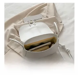 Detail view showing interior capacity with smartphone and wallet inside a white crossbody bag