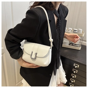 Detail of white minimalist underarm bag with silver U-shaped buckle and knotted leather strap
