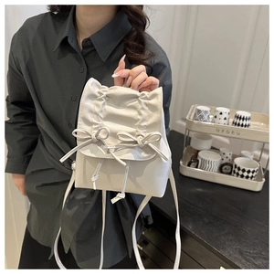 Detail of white pleated mini backpack with sweet bow accents and drawstring closure
