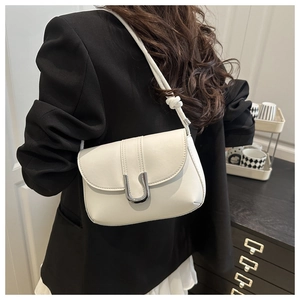 Close-up of cream leather shoulder bag with silver U-shaped buckle and knotted strap detail
