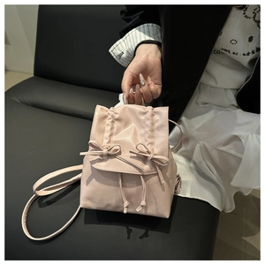 Detail of light pink ballet-style backpack with bow decor and pleated satin-like texture