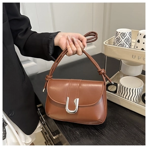 Detailed close-up of brown PU leather shoulder bag with a silver U-shaped metal buckle