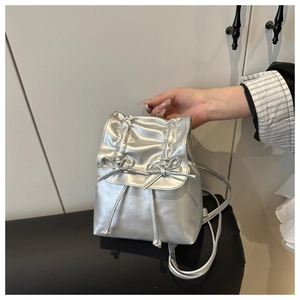 Detail of silver metallic mini backpack featuring ribbon bows and drawstring closure