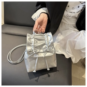 Detail of silver metallic backpack with drawstring pleats and delicate bow accents