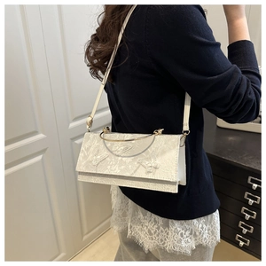Detail of white lace handbag with butterfly embroidery and golden metal handles