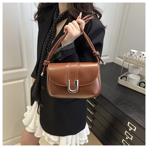 Close-up of brown shoulder bag featuring a silver U-shaped buckle and knotted handle