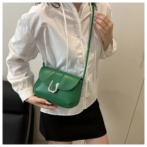 Close-up of a green leather underarm bag featuring a vintage silver U-shaped metal buckle